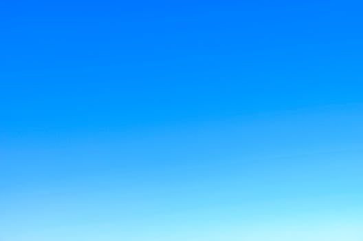 A serene view of a vibrant clear blue sky with a subtle gradient, perfect for backgrounds.